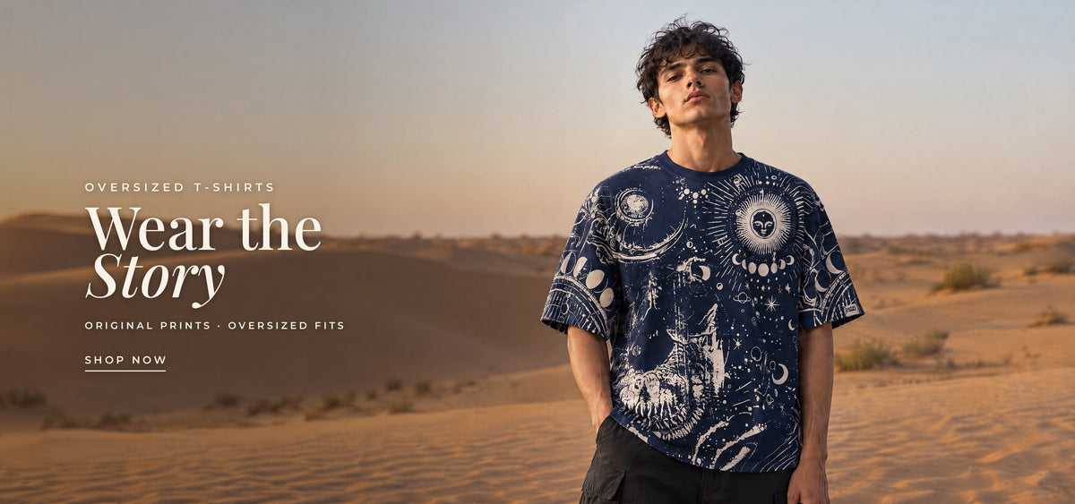 Oversized T-shirts: Wear the Story. Original prints, oversized fits. A man in the TRINETRA celestial-print tee among desert dunes. Shop T-shirts.