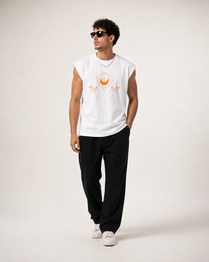 A man modeling a white sleeveless t-shirt with a graphic of a crescent moon and hands, paired with black sweatpants and white sneakers, against a plain light background.