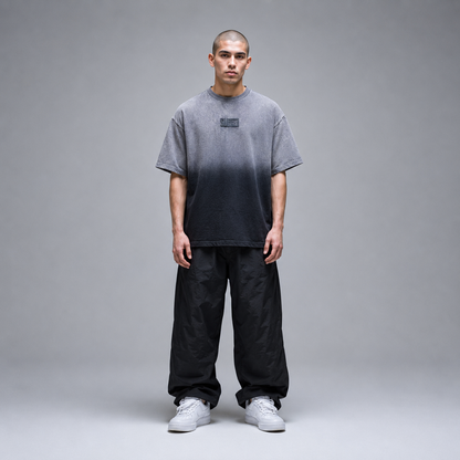 Person wearing a gray gradient t-shirt and black pants on a gray background