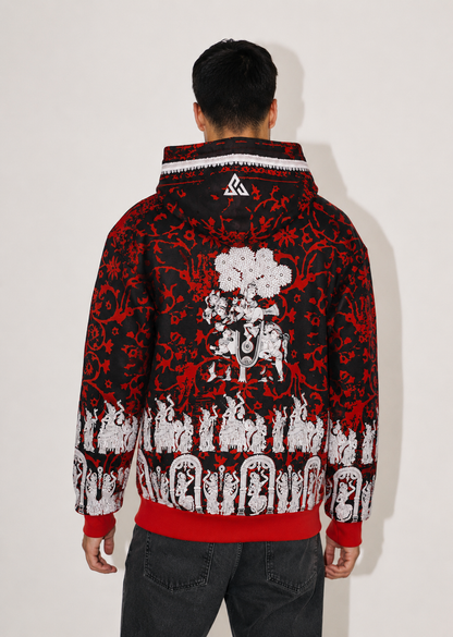 A man viewed from behind wearing a black and red hooded jacket with a white graphic print on the back, paired with dark gray jeans, against a plain off-white background.