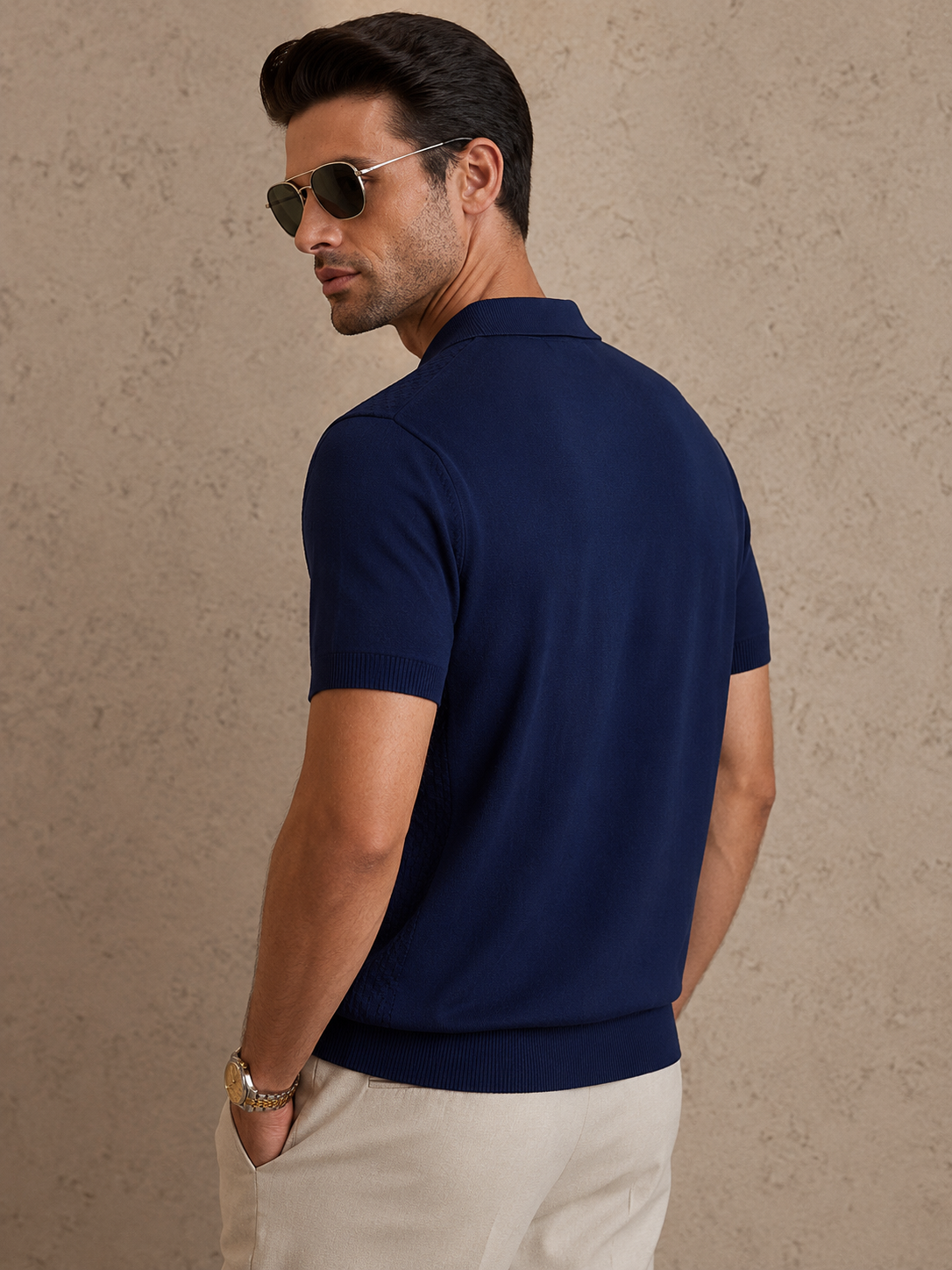 CORD knit polo in navy — three-quarter back view on model, shoulder turned to the camera