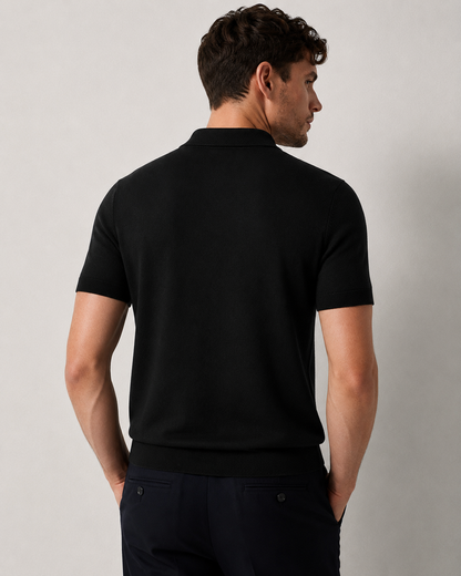 LEAF Knit Polo in black — back view on model, plain-knit back and ribbed hem over navy trousers