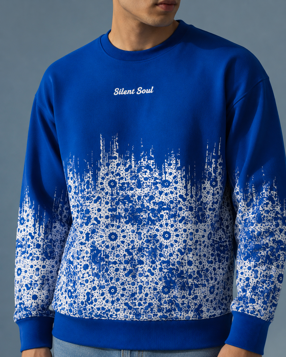 A man wearing a royal blue crewneck sweatshirt with a white floral pattern gradient fading from the hem to the cuffs, featuring the text 'Silent Soul' on the chest.