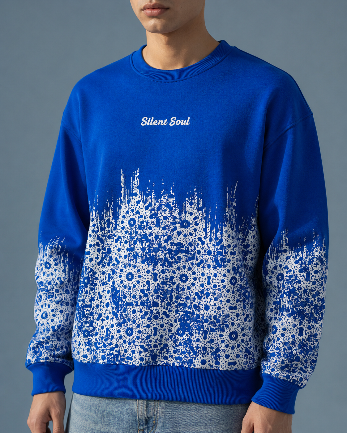 A man wearing a royal blue crewneck sweatshirt with a white floral pattern gradient on the lower half and sleeves, featuring the text 'Silent Soul' printed in white on the chest.