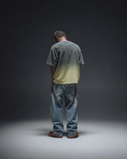Ombrix tee in olive fading to sage — full-length back view on model, styled with faded baggy jeans