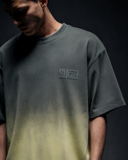 Ombrix tee in olive fading to sage — torso view on model, tonal Sunya badge boxed at the chest