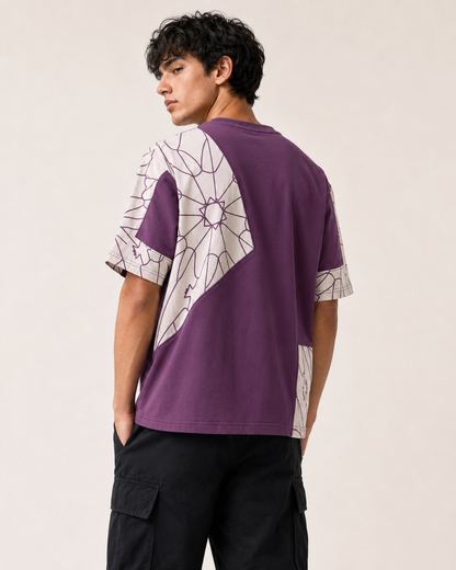 A man wearing a purple and white geometric patterned t-shirt, shown from the back against a plain light beige background.