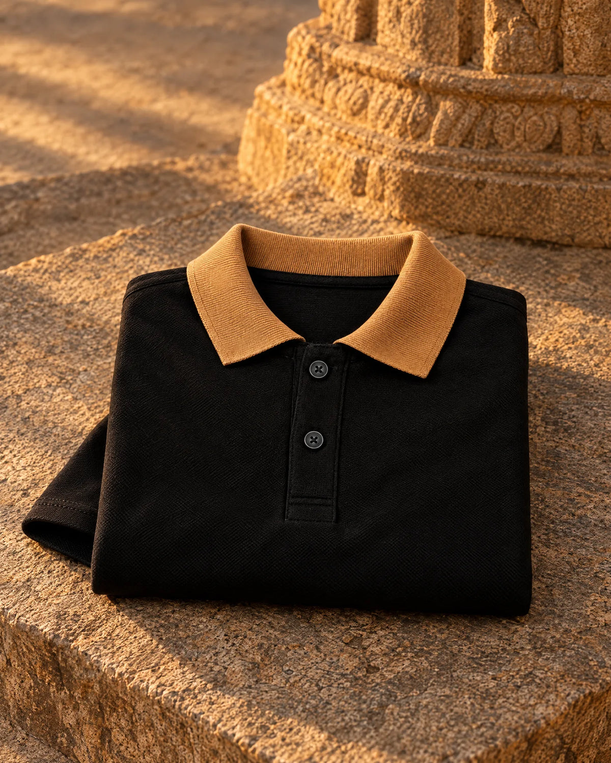 The black Full Sleeve Oxford Polo folded on a granite temple step, camel collar and two-button placket on top