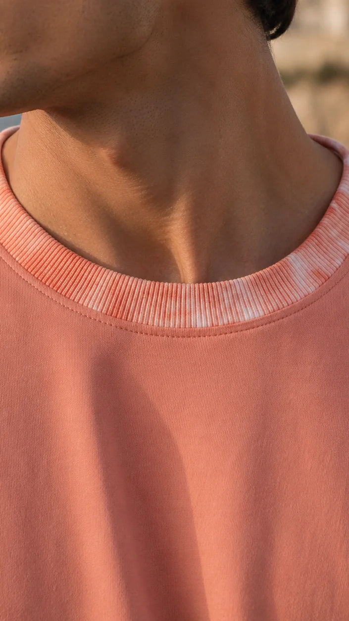 Close-up of the coral tie-dye patterned rib collar on a coral tee