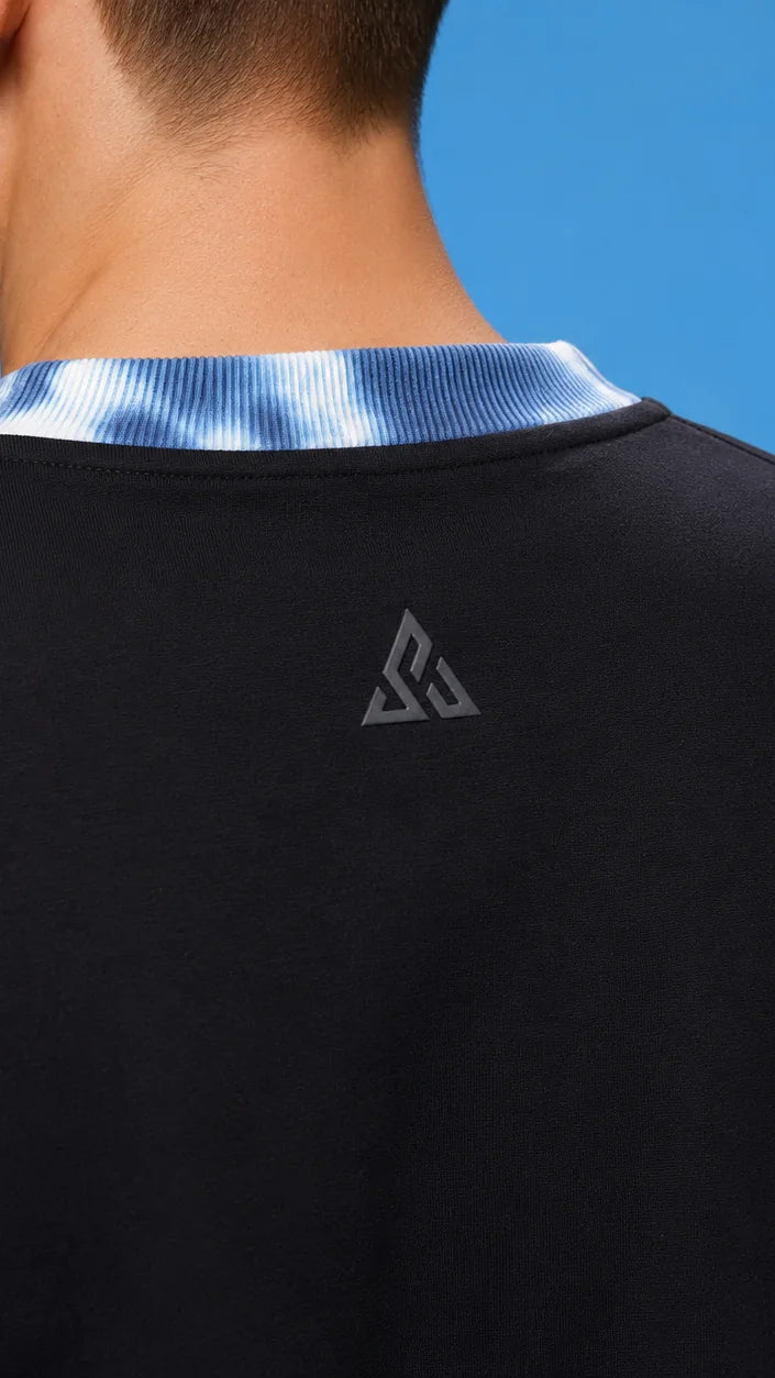 Back view of a black tee with a tie-dye blue rib collar and a single grey emblem