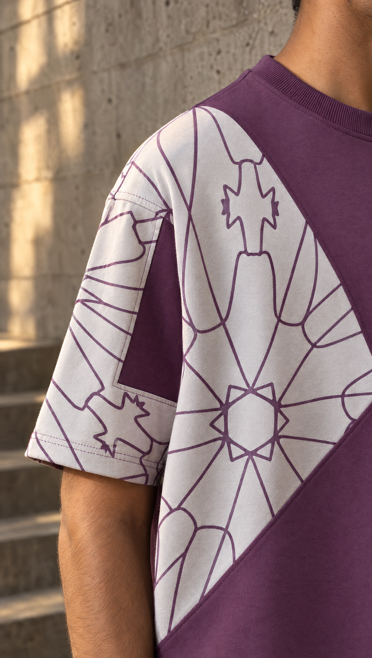 Petra tee: the sand star-tessellation panel over the dropped shoulder of the plum body