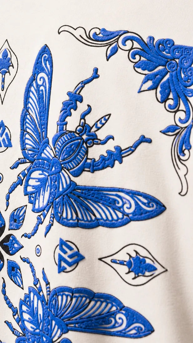 Strex tee: cobalt beetle and scrollwork print on the bone-white back
