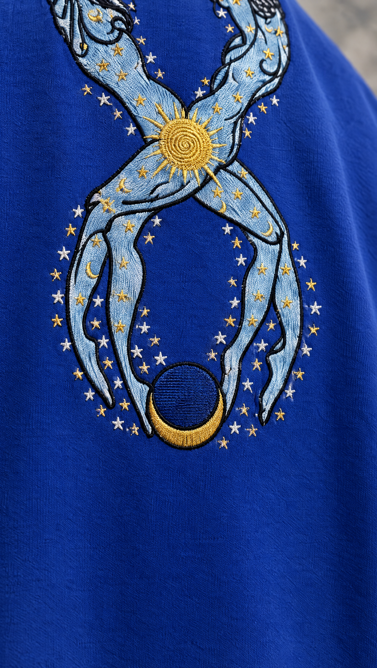 Close-up of the gold sun and powder-blue figures on the back of the royal-blue Eternal Truth tee