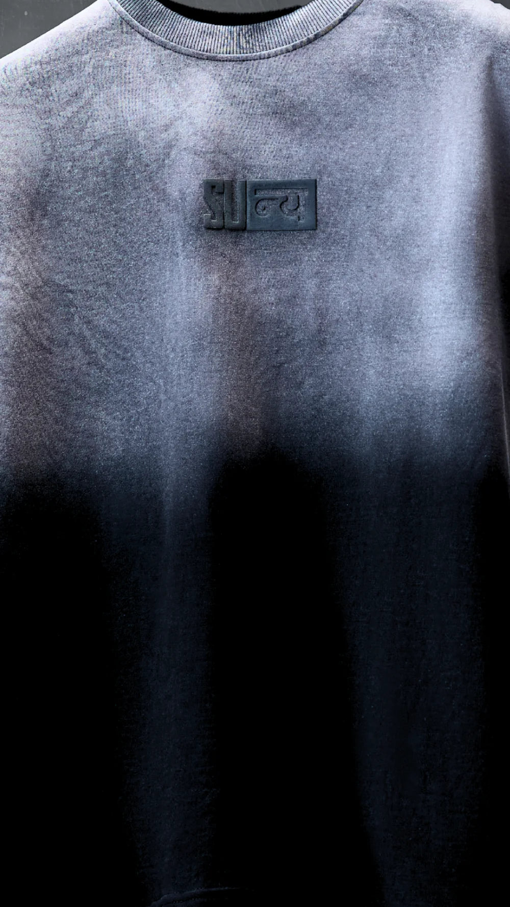Close-up of the charcoal chest badge and the ash-grey to charcoal fade