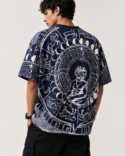 A man wearing a navy blue t-shirt with a large white celestial and occult-style graphic print on the back, shown from behind against a light gray studio background.